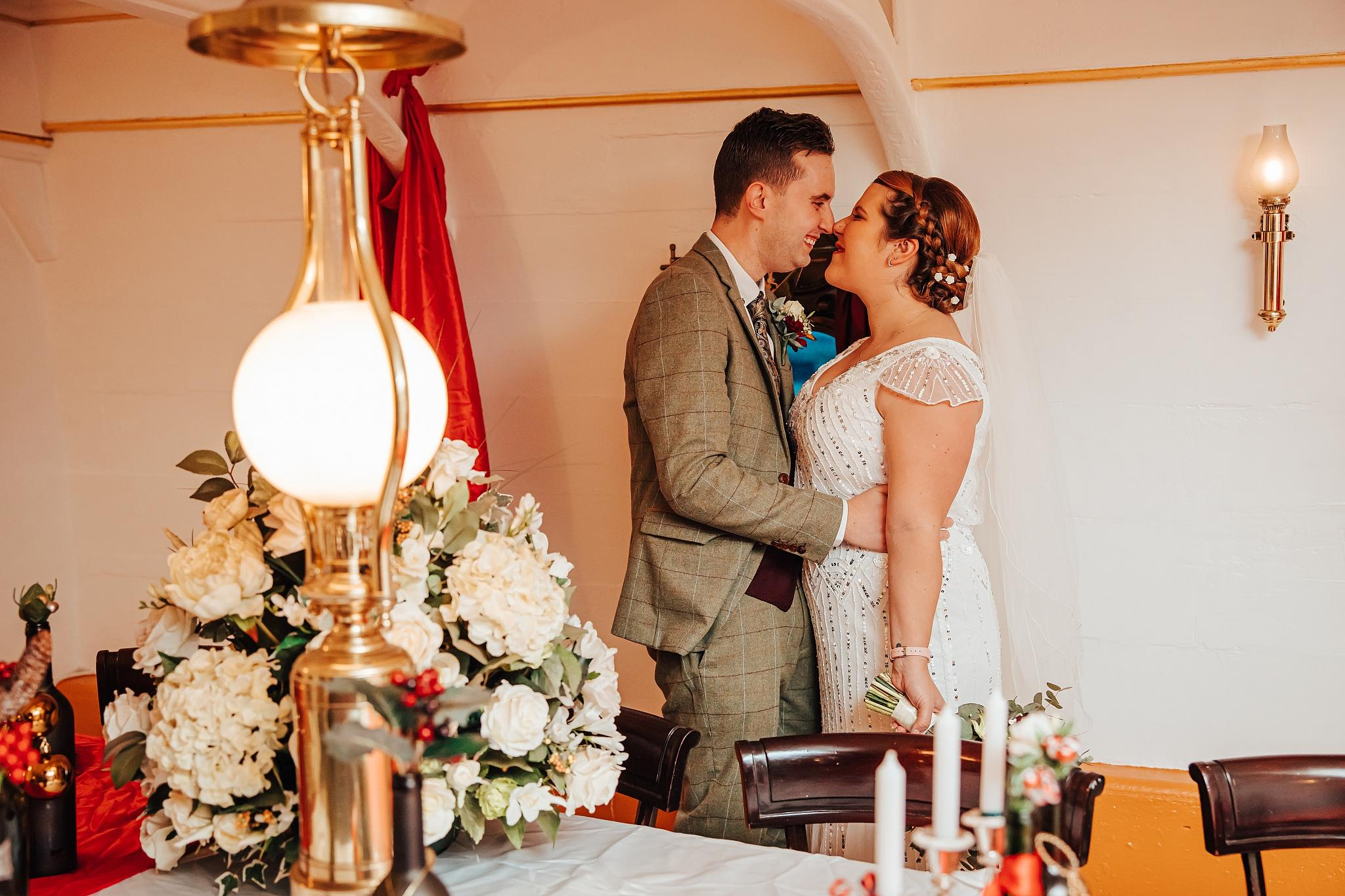 A bride and groom touch noses onboard HMS Warrior during their 1920s themed wedding. 