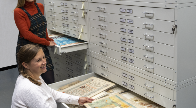 Two women next to open drawers full of documents