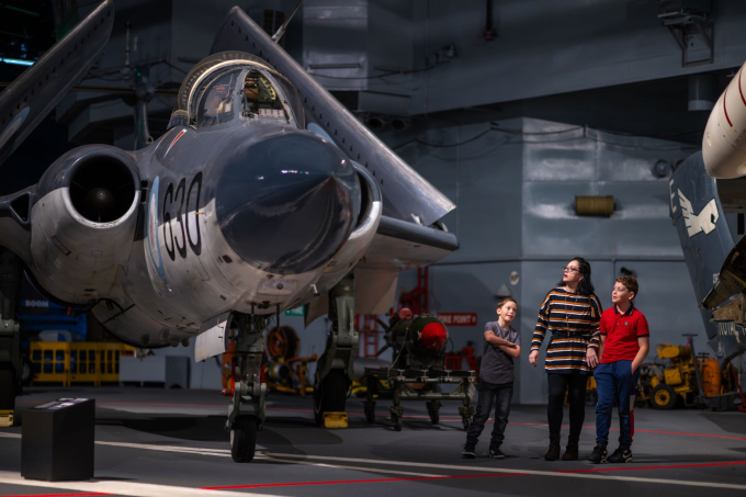 Mother and sons look up at a Royal Navy aircraft