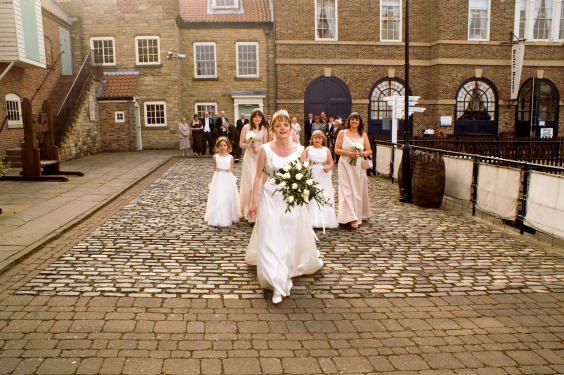 Bridal party walking on quayside towards HMS Trincomalee