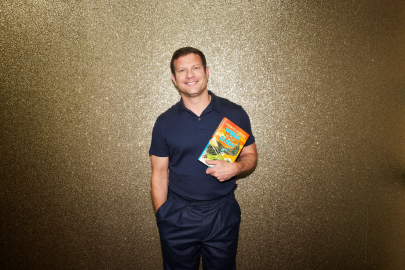 Dermot O'Leary holding a copy of his book 'Wings of Glory'