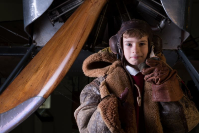 A young boy is dressed as a First World War pilot. 