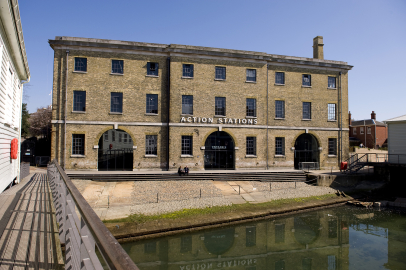 The front of a large historic building with a sign that says 'Action Stations'