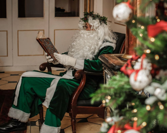 Santa sat by a tree reading a book