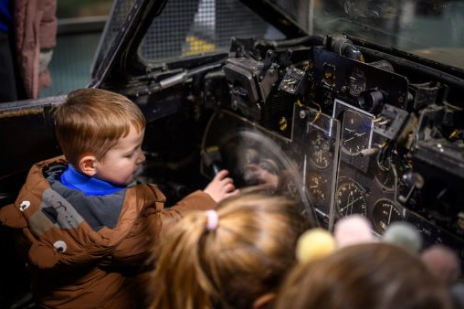 Three small children touch aircraft controls at the Fleet Air Arm Museum