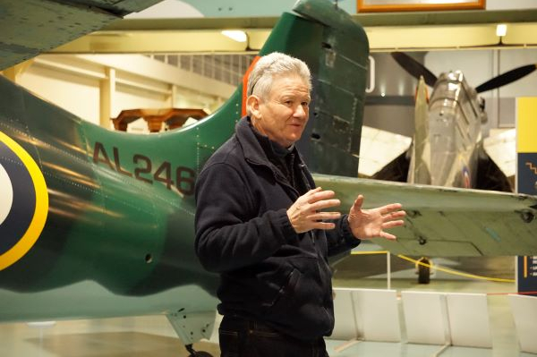 Elderly volunteer gives talk in front of historic aircraft at the Fleet Air Arm Museum