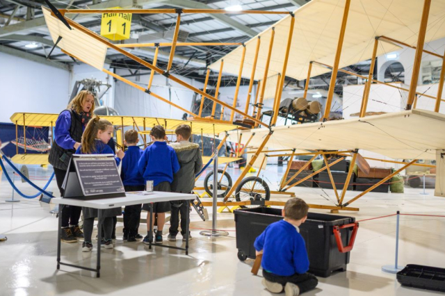 A school group look at one of the oldest planes in existence. The plane is made with wood and paper.  