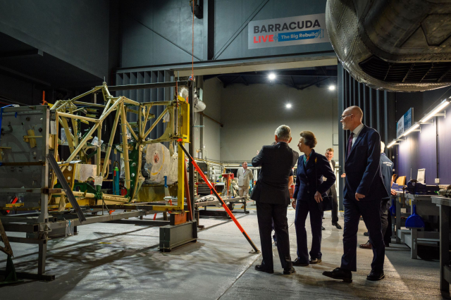 Three figures look on at the ongoing work to rebuild a Fairey Barracuda