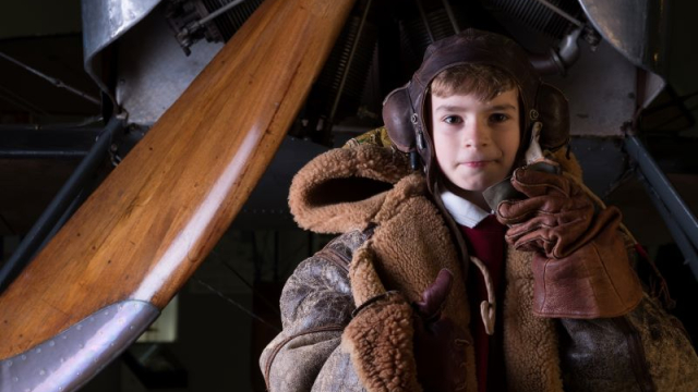 A young boy is dressed as a First World War pilot. 