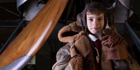 A young boy is dressed as a First World War pilot. 